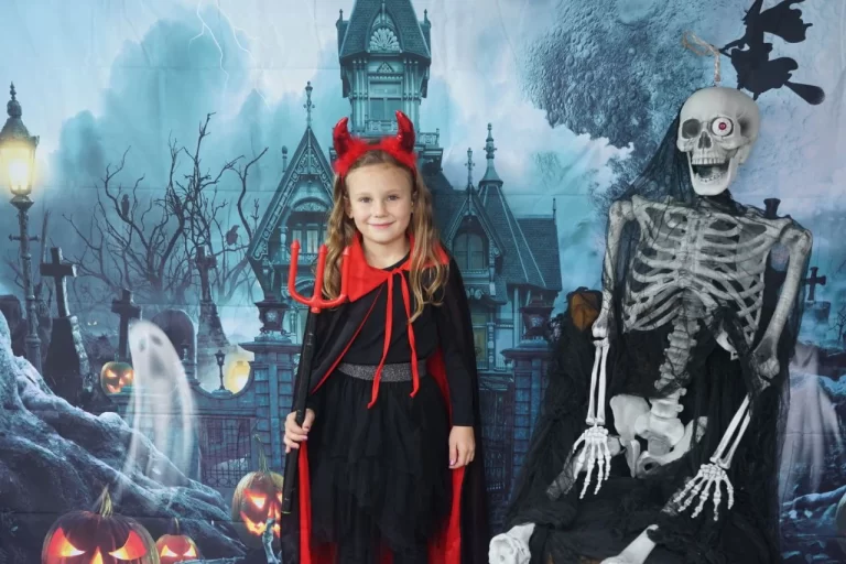 A young girl in an enchanting Halloween costume, beaming with joy, set against a softly blurred outdoor backdrop.